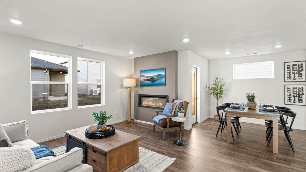 Addysen Park great room with an electric fireplace, couches, coffee table, windows, blinds, flooring, and dining room in the background