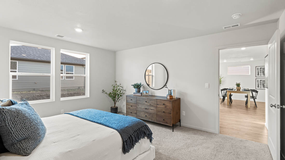 Addysen Park Primary bedroom with carpet, bedroom with pillows, dresser, windows, nightstand with lamp, and the en suite bathroom in the background