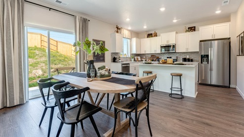 Avery Terrace Dining room with a table set for six chairs and the kitchen with stainless steel appliances