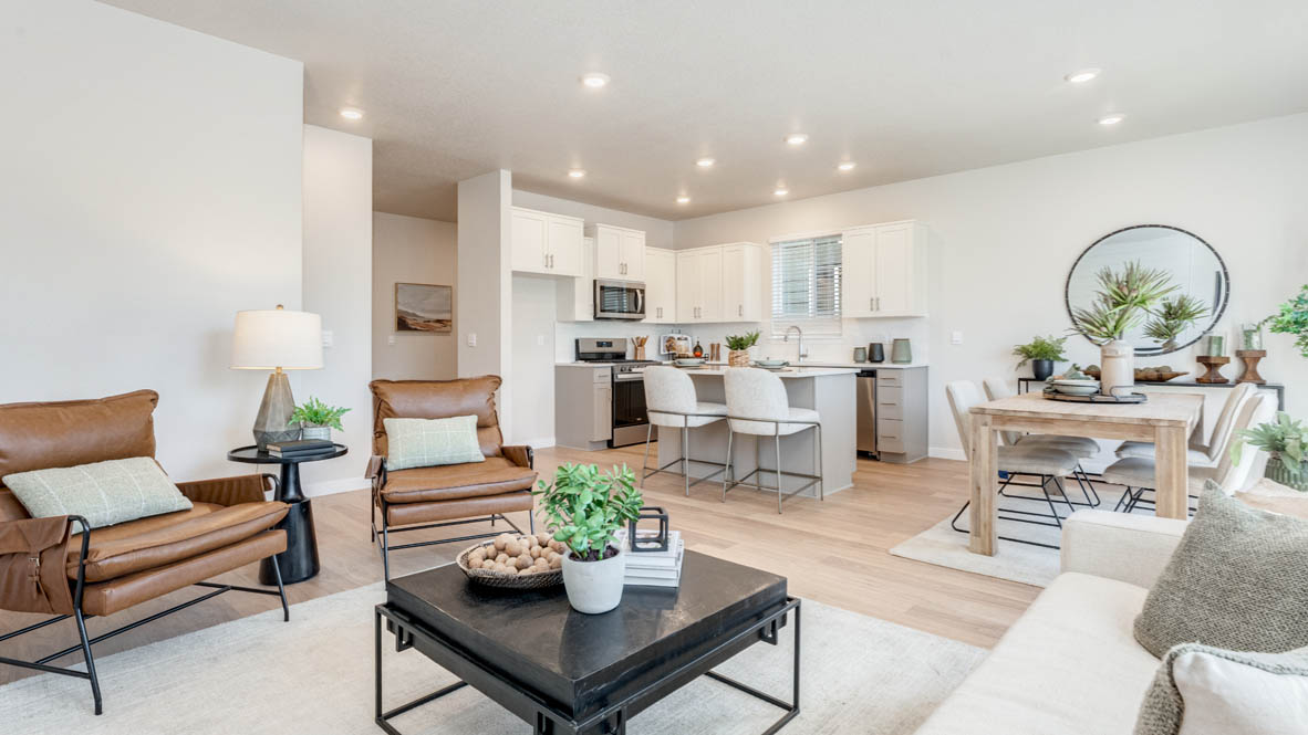 Avery Terrace great room with laminate flooring, white carpet, a brown chair, entertainment center, white couch, glass coffee table, plants, paintings, and a tv, view of dining room and kitchen