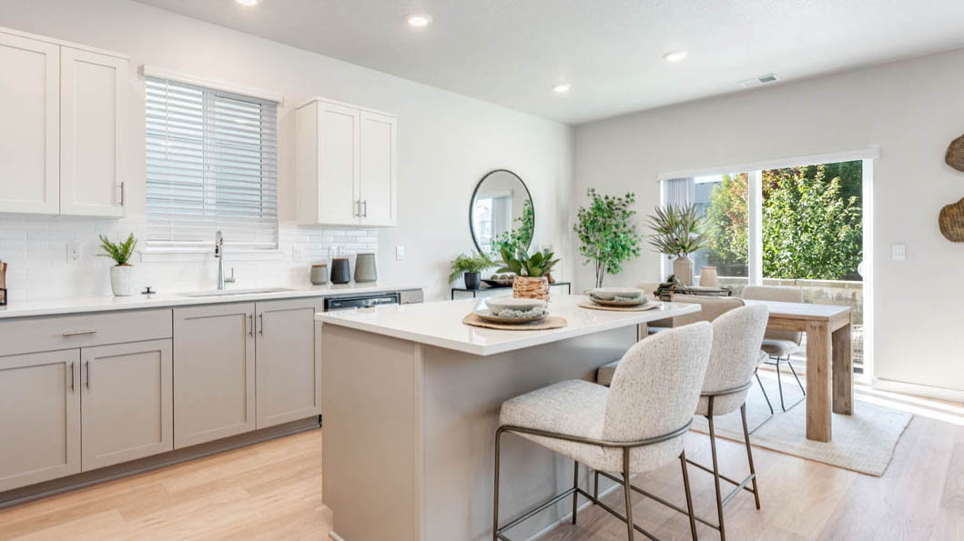 Avery Terrace Kitchen with island and a breakfast bar, two chairs, white cabinets, stainless steel appliances, quartz countertops, a window, decorations, and laminate flooring