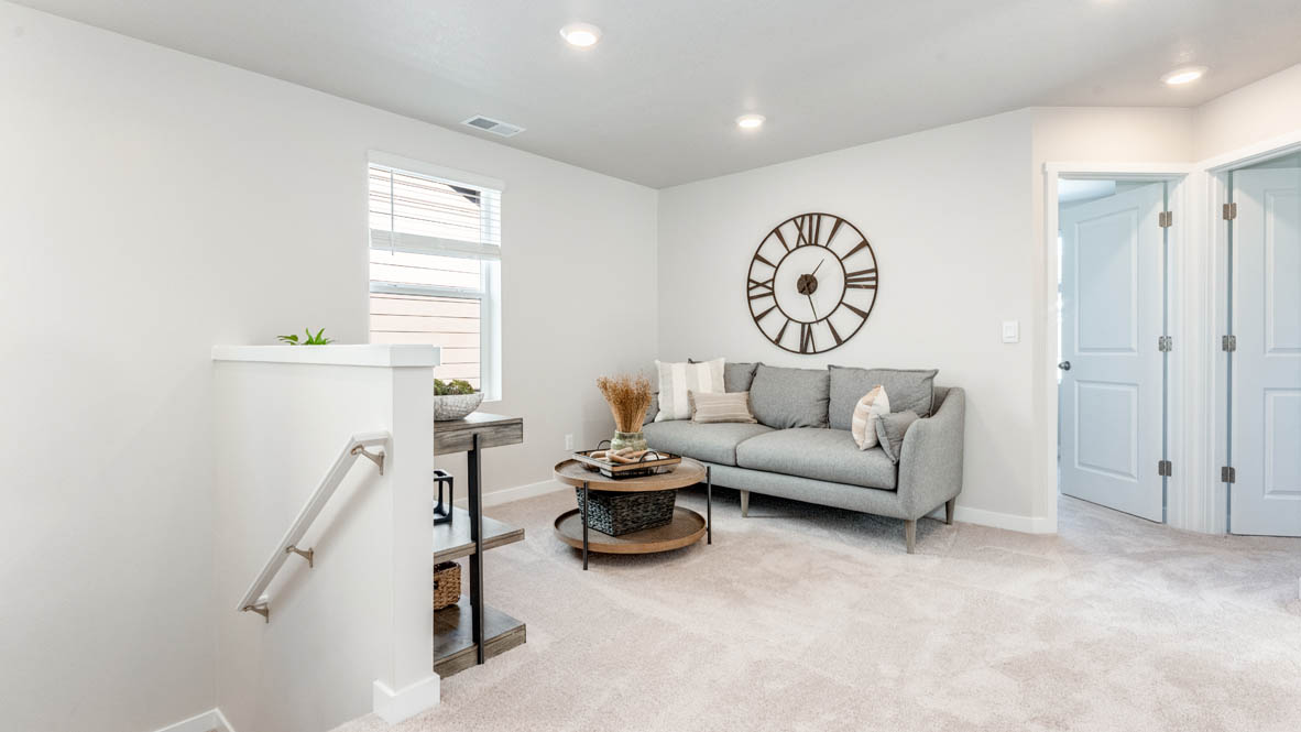 Avery Terrace Loft with carpet, stairs, cofee table, gray chair, big clock, and table with a window, and view of bedrooms