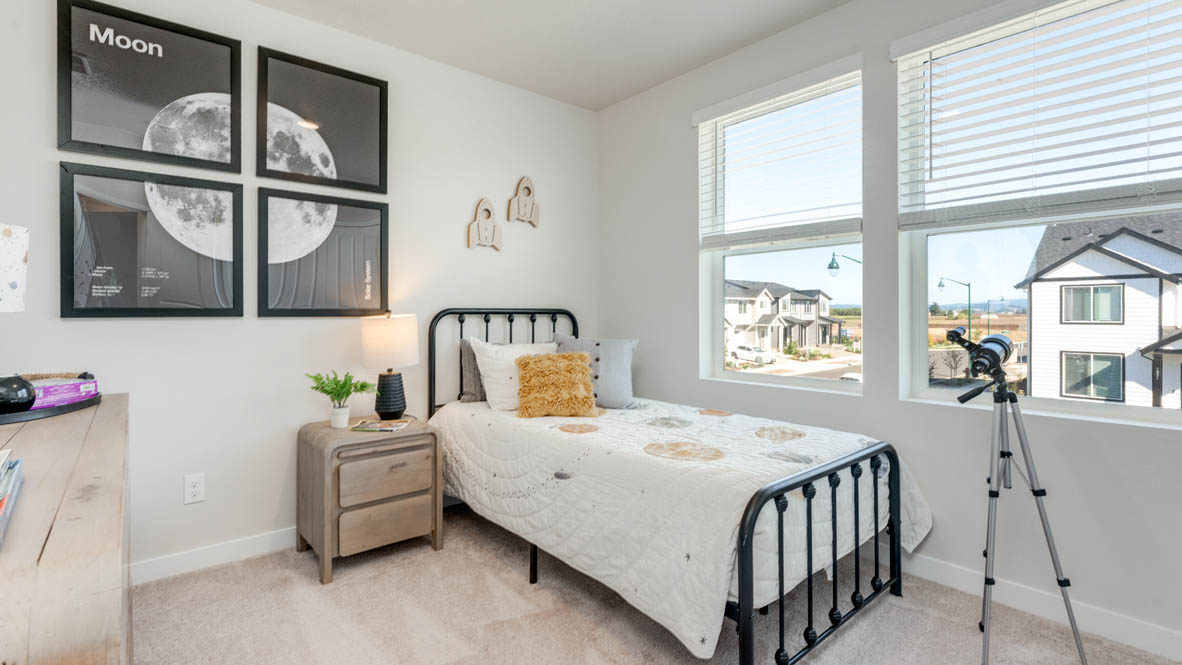 Avery Terrace Bedroom with a bed with sheets, light stained bed frame, end table with a lamp, paintings, and a window, and a telescope