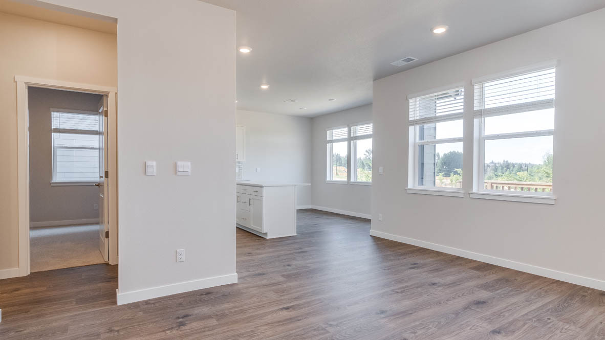 Avery Terrace Great Room with laminate flooring, windows, white walls, and the bedroom in the background