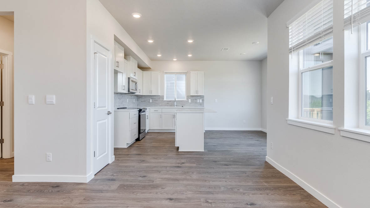 Avery Terrace great room with winows, white walls, and the kitchen in the background