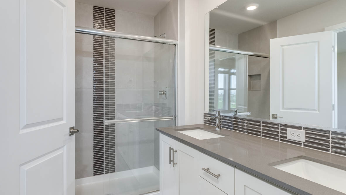 Avery Terrace primary bathroom with a double vanity, gray quartz countertops, mirror, and a walk in shower