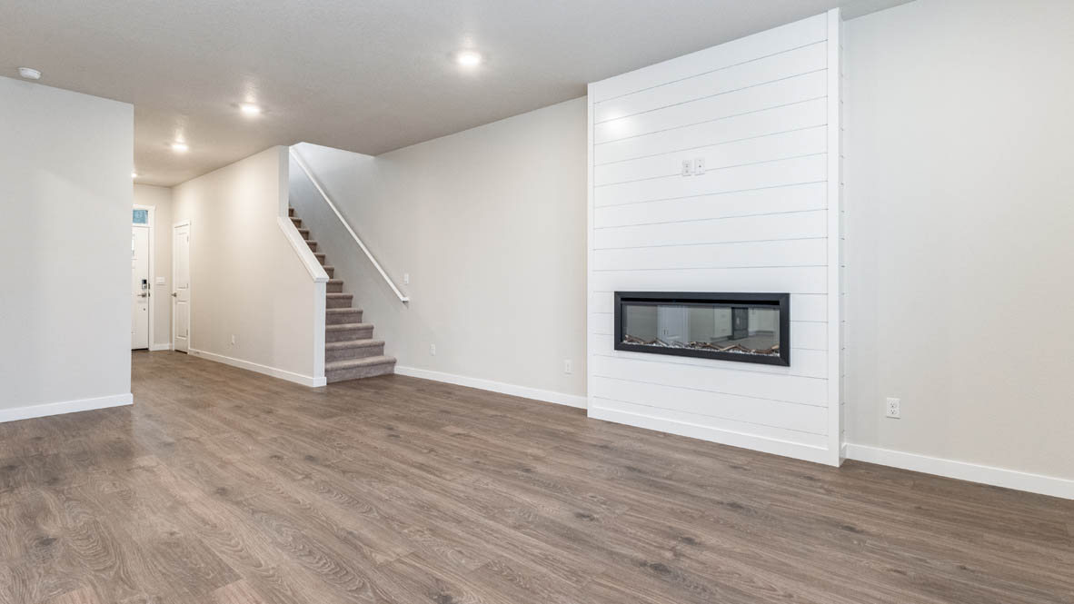 Avery Terrace great room with staircas, white walls, and fireplace