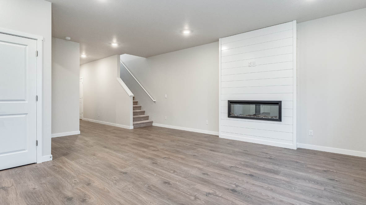 Avery Terrace great room with staircas, white walls, and fireplace