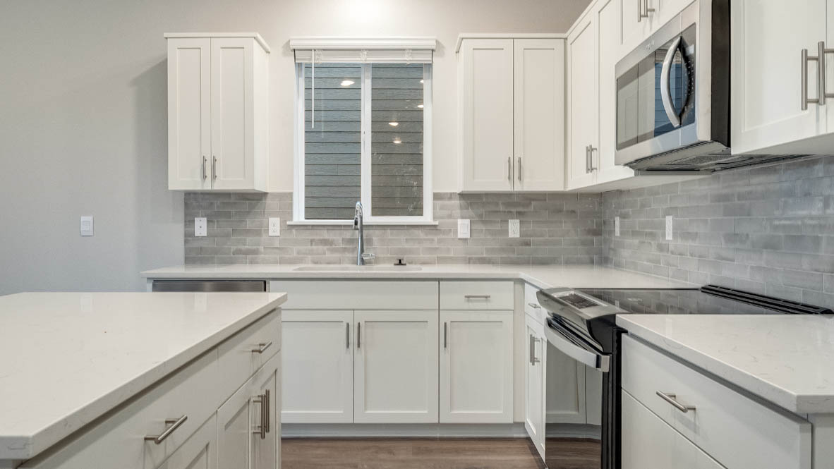 Avery terrace Kitchen with quartz countertops, island, stainless steel appliances, cabinets, and a window