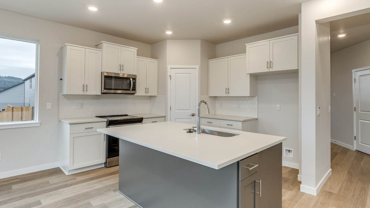 Kitchen with shaker cabinets, quartz counters, stainless steel appliances, pantry, and an island with a breakfast bar