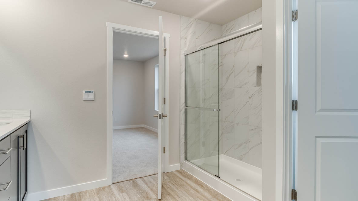 Avery Terrace primary bathroom with mirror, cabinets, walk in closet, solid surface countertops