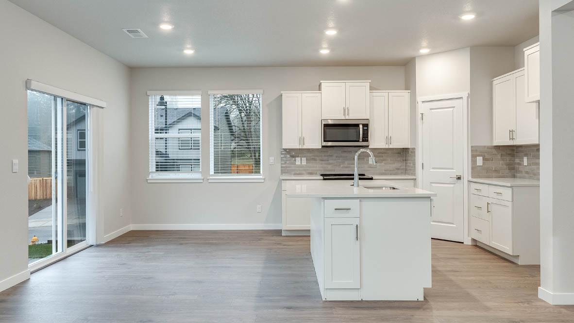Kitchen with shaker cabinets, quartz counters, stainless steel appliances, pantry, and an island with a breakfast bar