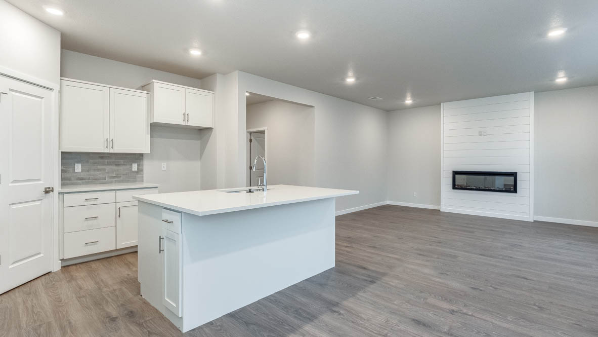 Kitchen with shaker cabinets, quartz counters, stainless steel appliances, pantry, and an island with a breakfast bar