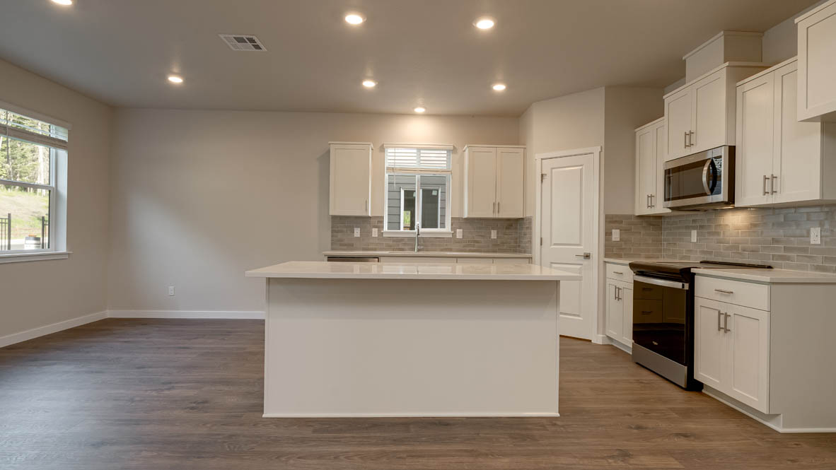Kitchen with shaker cabinets, quartz counters, stainless steel appliances, pantry, and an island with a breakfast bar