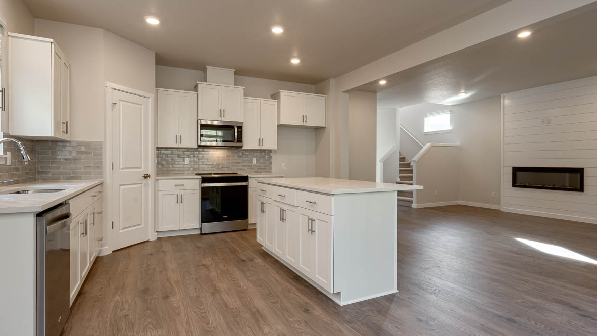 Kitchen with shaker cabinets, quartz counters, stainless steel appliances, pantry, and an island with a breakfast bar