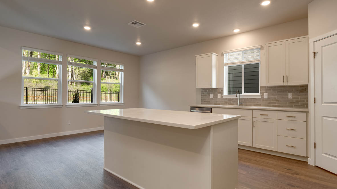 Kitchen with shaker cabinets, quartz counters, stainless steel appliances, pantry, and an island with a breakfast bar
