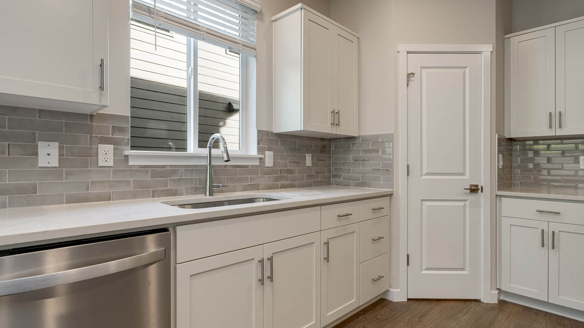 Kitchen with shaker cabinets, quartz counters, stainless steel appliances, pantry, and an island with a breakfast bar