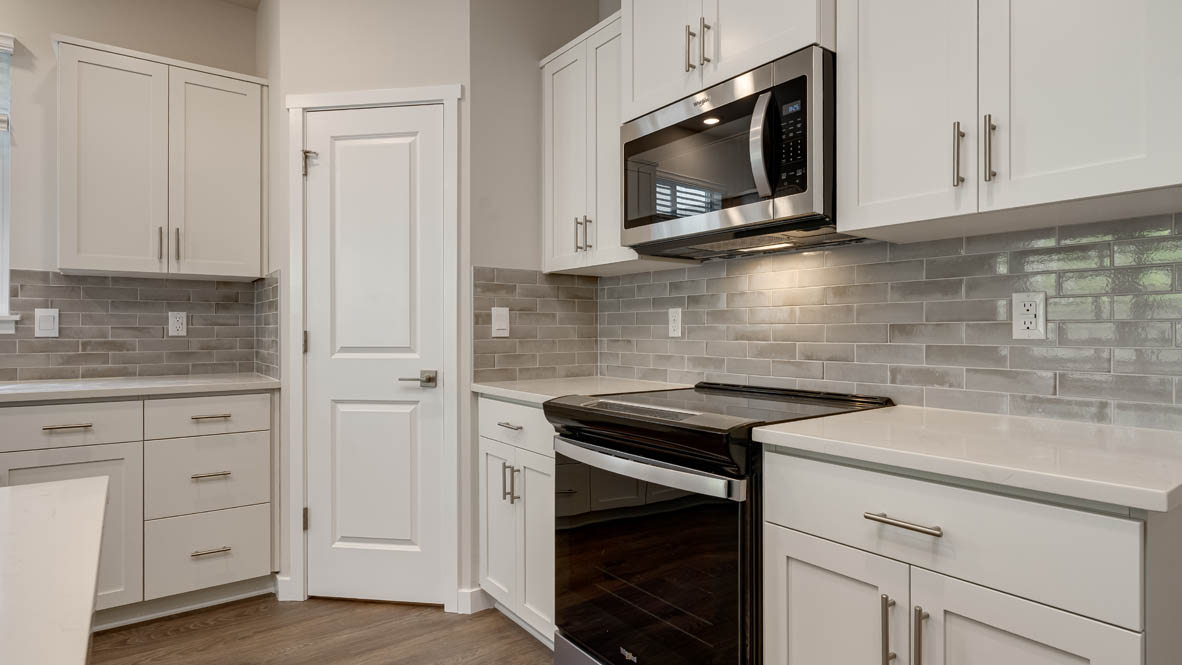 Kitchen with shaker cabinets, quartz counters, stainless steel appliances, pantry, and an island with a breakfast bar