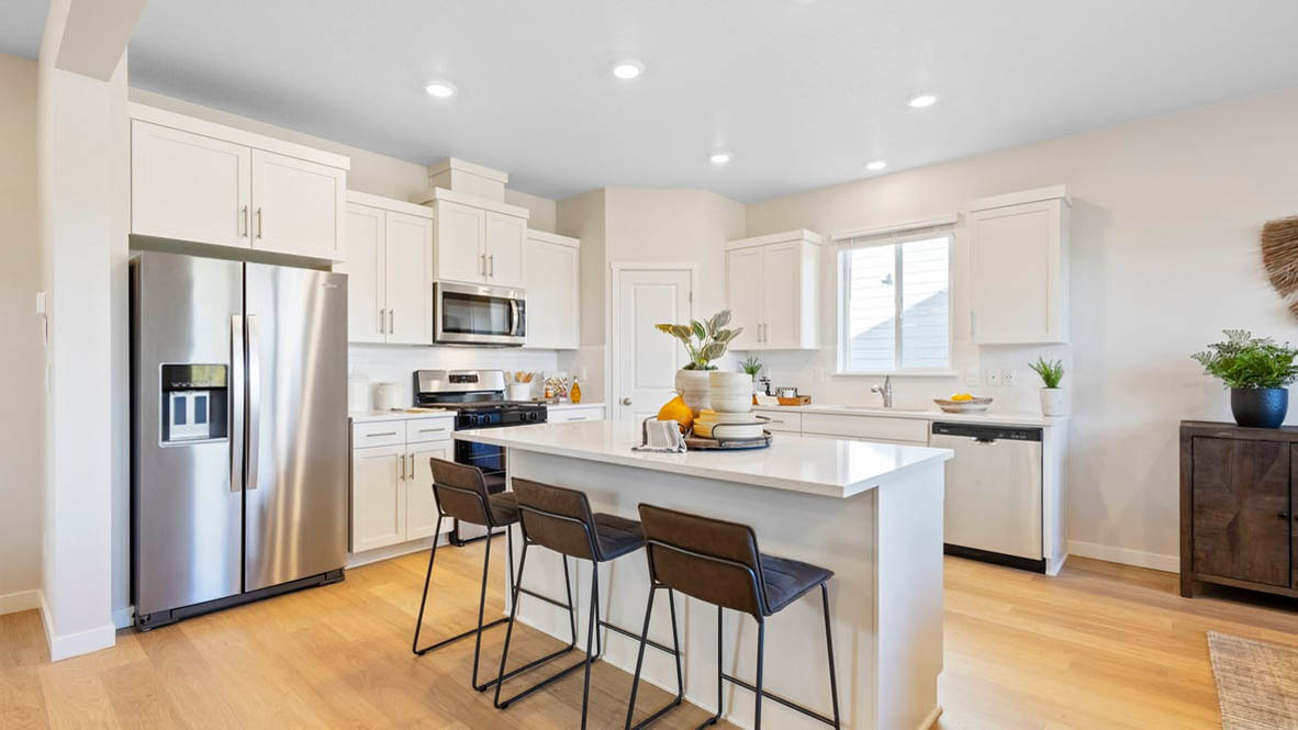 Avery Terrace Kitchen with island and a breakfast bar, two chairs, white cabinets, stainless steel appliances, quartz countertops, a window, decorations, and laminate flooring