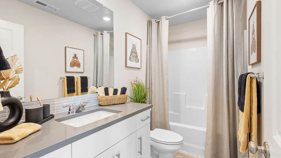 Avery Terrace Bathroom with white quartz countertops, mirrors, plants, toilet, and a bathtub