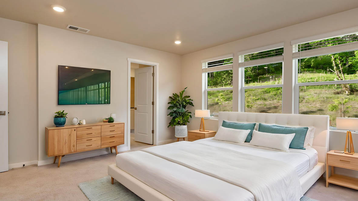 Avery Terrace Primary bedroom with a large bed with two side tables one on either side of the bed. Carpeted flooring and windows