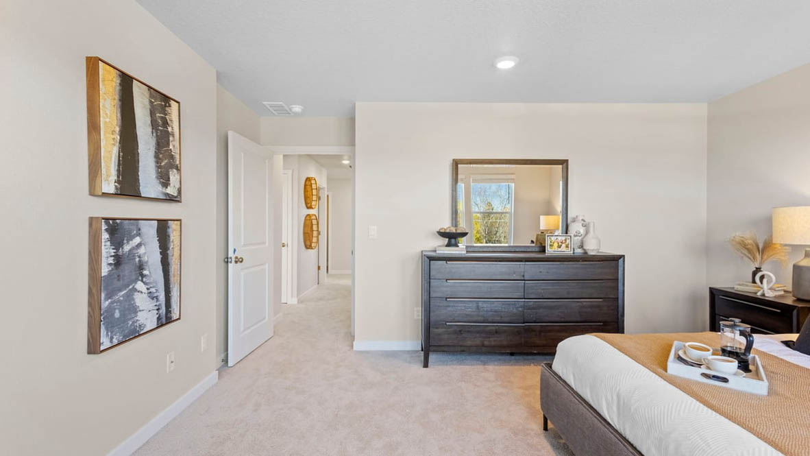 Avery Terrace Primary bedroom with carpet and a bed with a white bedframe, two end tables, two lamps, pillows, windows, and plants
