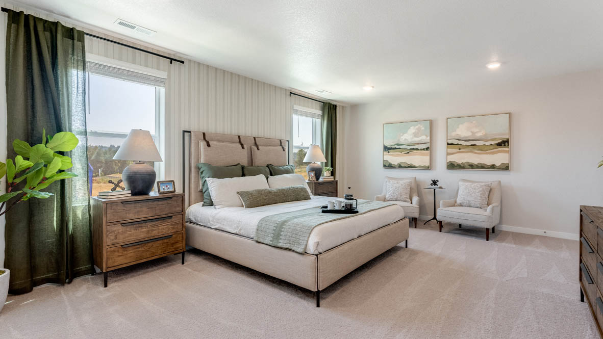 Avery Terrace Primary bedroom with a stripped wallpaper accent wall, large bed with two accent chairs against once wall and two side tables one on either side of the bed. Carpeted flooring and green window drapes