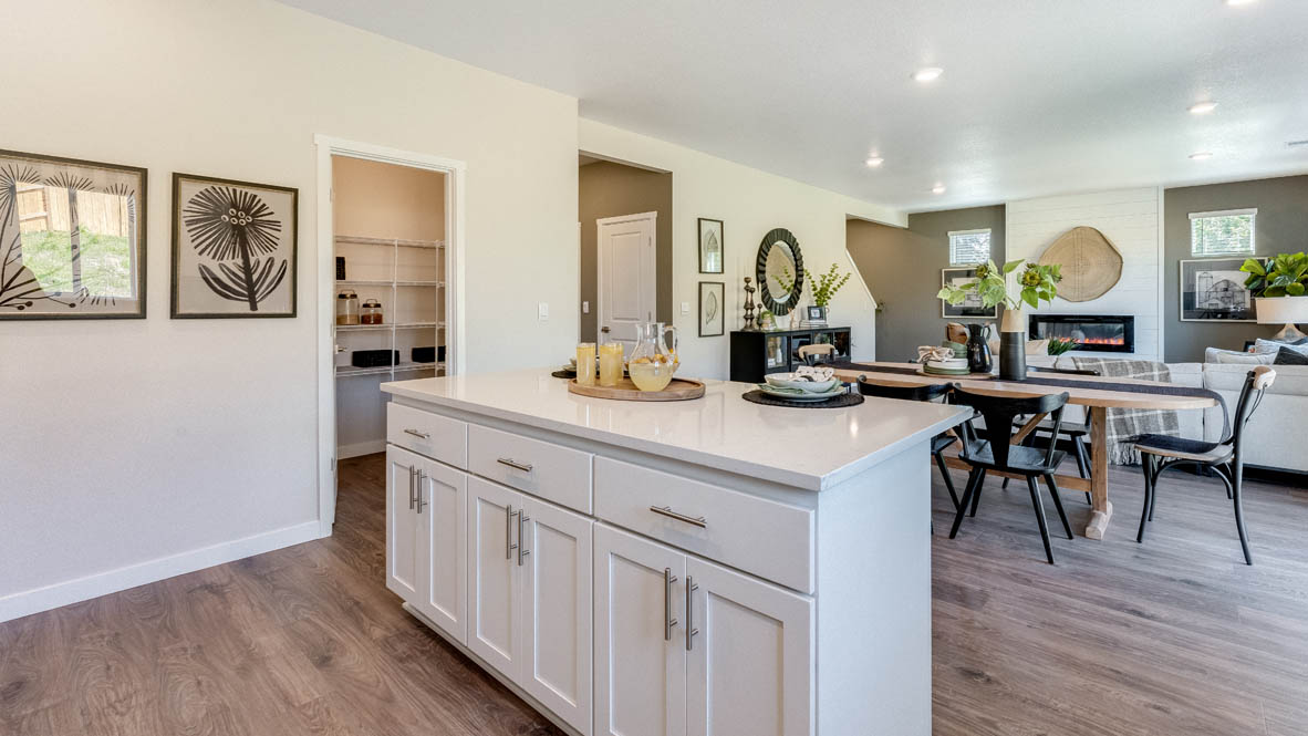 Avery Terrace Kitchen with two stools seated at the island, white quartz countertops, white shaker style cabinets, and stainless steel appliances