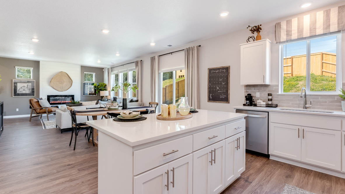 Avery Terrace Kitchen with two stools seated at the island, white quartz countertops, white shaker style cabinets, and stainless steel appliances