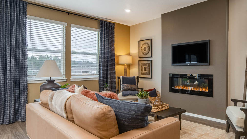 Avery Terrace great room with electric fireplace and painted accent wall, tv, windows, blue drapes, orange couch, coffee table, chair