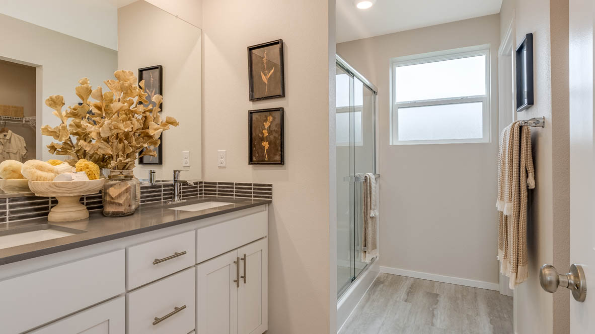 Avery Terrace primary bathroom with solid surface countertops, cabinets, mirror, stained glass window, walk inshower
