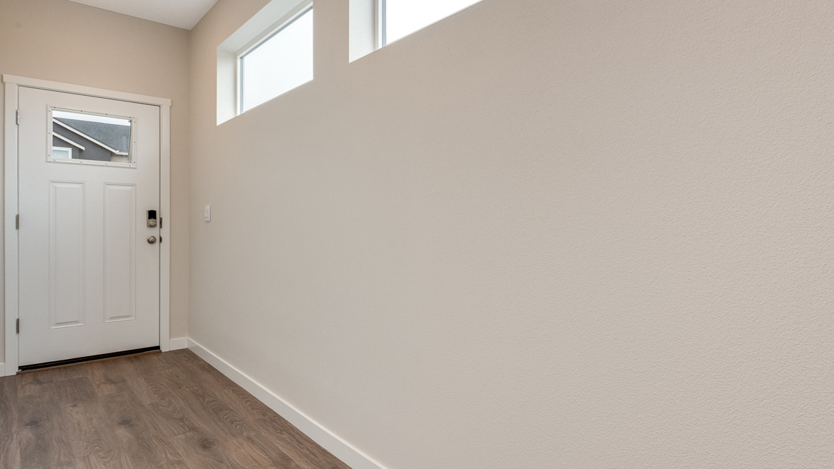 Avery Terrace entry with white walls, door, and two windows with laminate flooring