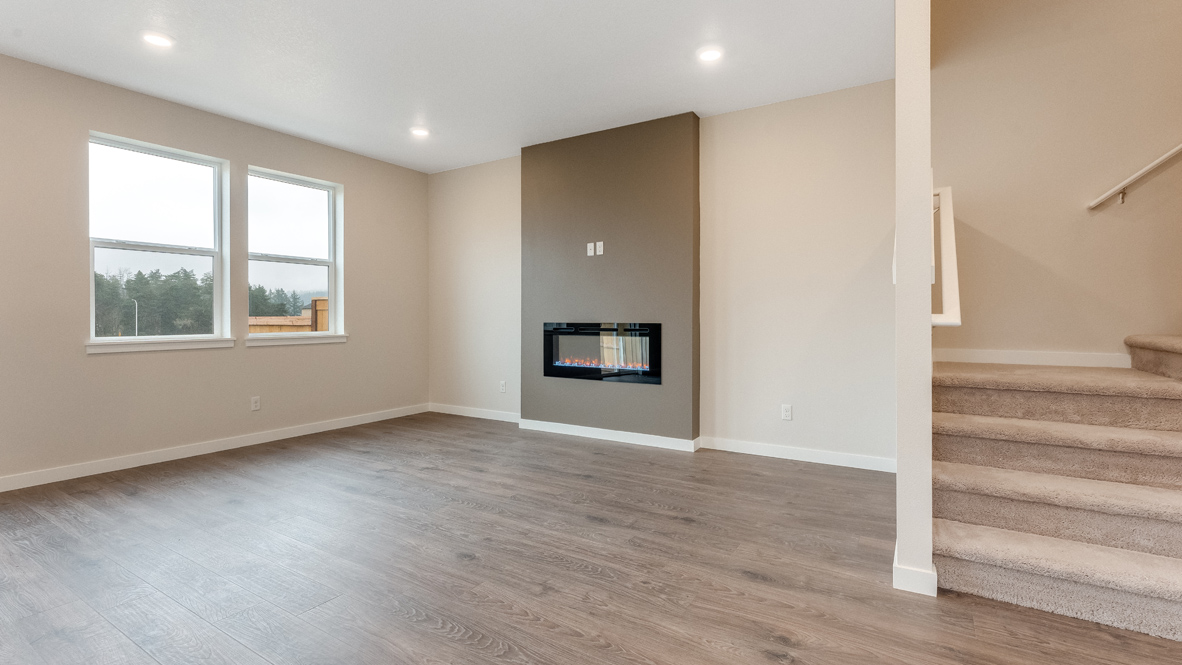 Avery Terrace great room with laminate flooring, windows, electric fireplace, accent wall, and staircase