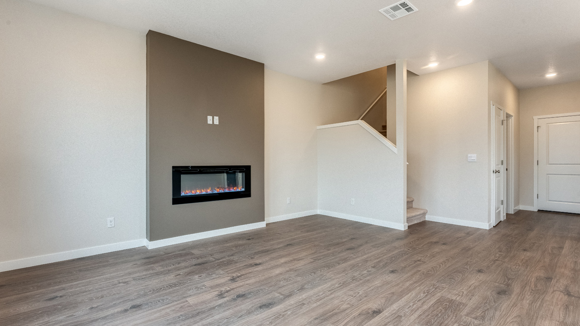 Avery Terrace great room with laminate flooring, windows, electric fireplace, accent wall, and staircase
