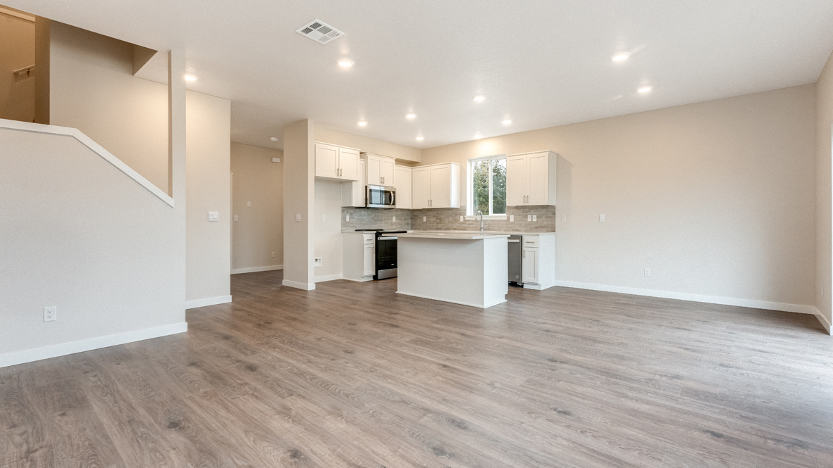 Avery Terrace kitchen with laminate flooring, white walls, lights, view of kitchen with an island, stainless steel appliances, and a window