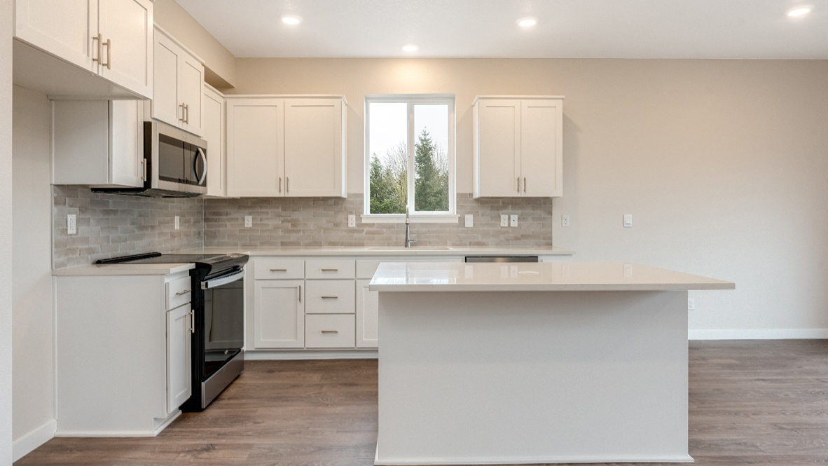 Avery Terrace kitchen with stainless appliances, quartz countertops, an island, a window, soft close cabinetry, laminate flooring, white walls