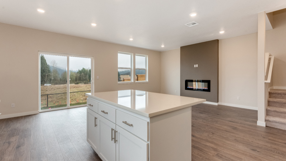 Avery Terrace kitchen and great room with laminate flooring, an island with quartz countertops, soft closed cabinets, electric fireplace with accent wall, sliding glass door, two windows