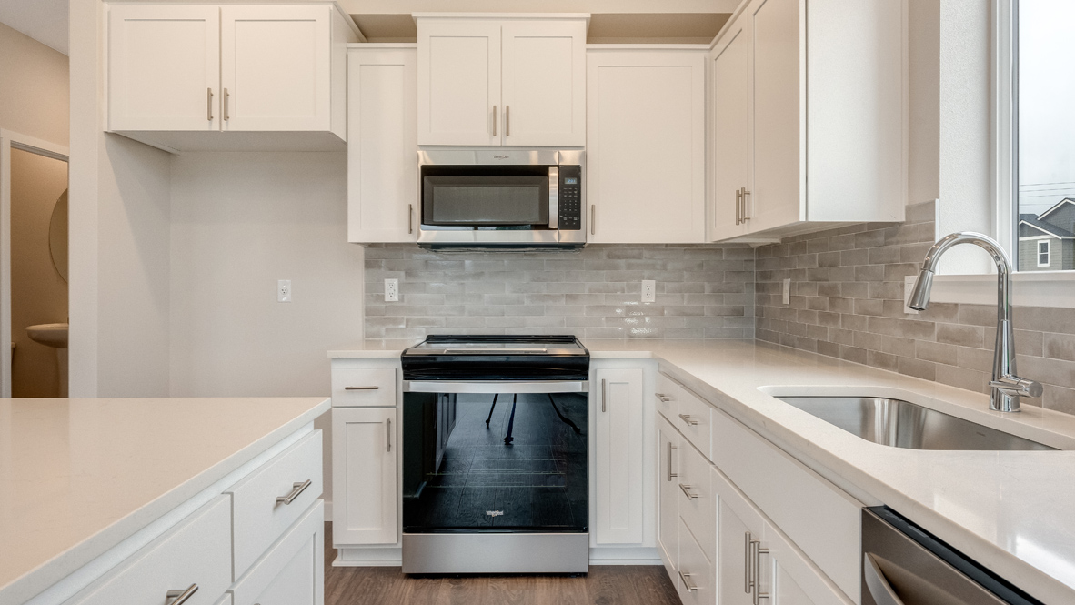 Avery Terrace kitchen with stainless appliances, quartz countertops, an island, a window, soft close cabinetry, laminate flooring, white walls