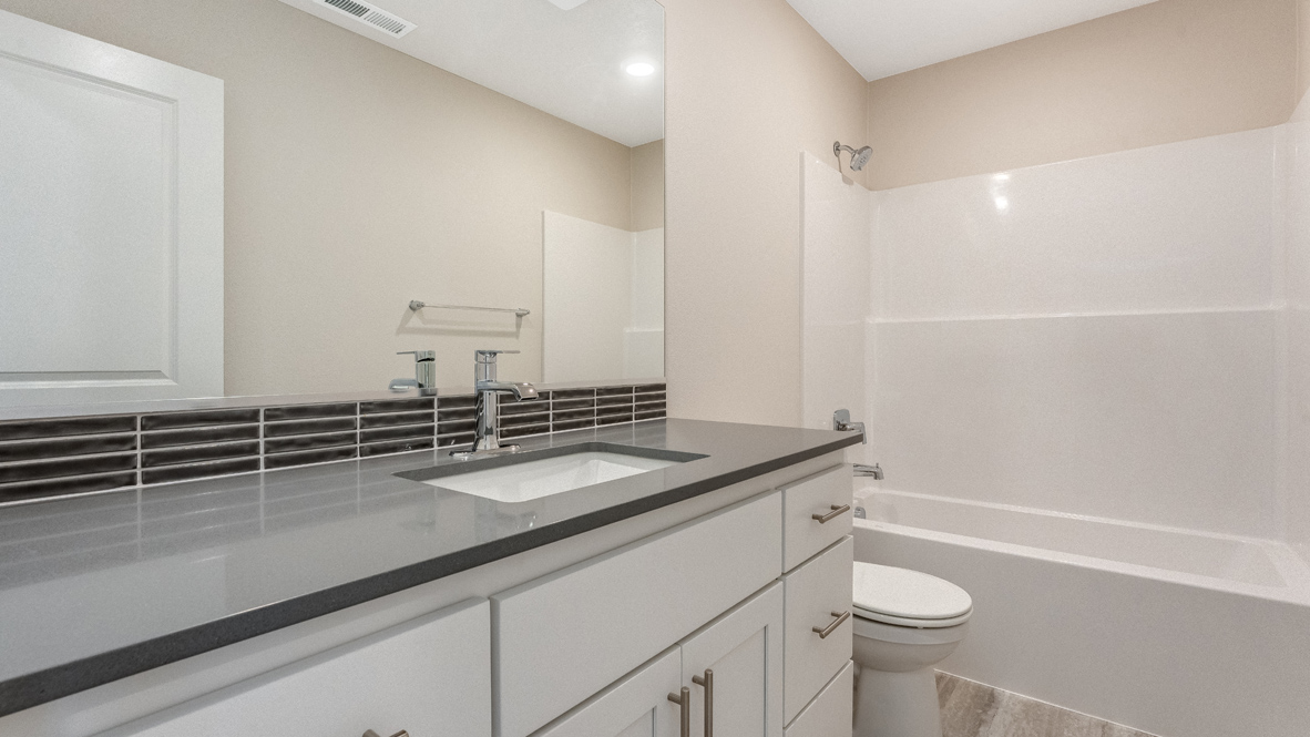 Avery Terrace secondary bathroom with quartz countertops, soft close cabinets, mirror, toilet, and bathtub