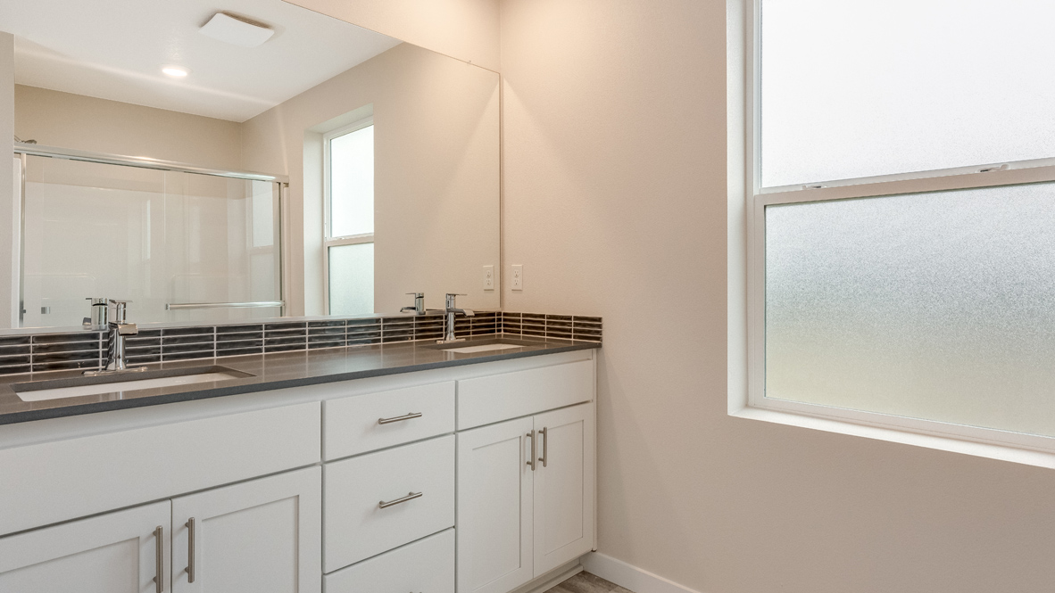 Avery Terrace primary bathroom with quartz countertops, cabinets, stained glass window, mirror