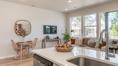 Gordon Creek Pointe Kitchen with stool chairs, quartz countertops, island peninsula, stainless steel appliances, white cabinets, and the dining room in the background