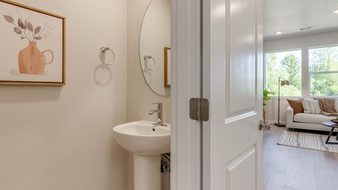 Gordon Creek Pointe Powder room with single vanity, painting, mirror, and the great room in the background