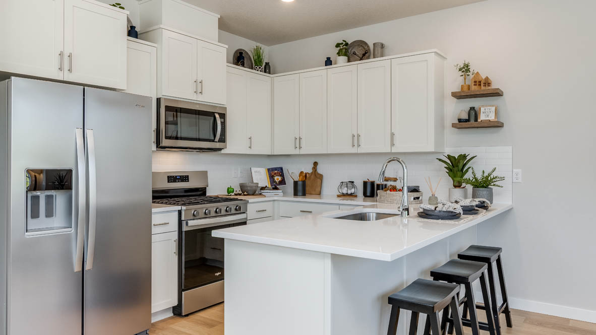 Gordon Creek Pointe Kitchen with a peninsula, barstool chairs, laminate flooring, quartz countertops, stainless steel appliances, drawers