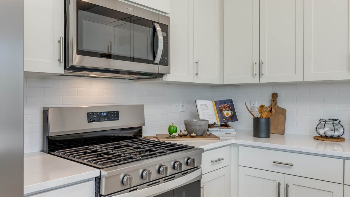 Gordon Creek Pointe Kitchen with a peninsula, barstool chairs, laminate flooring, quartz countertops, stainless steel appliances, drawers