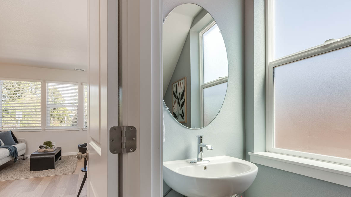 Gordon Creek Pointe powder room with single sink vanity, stained window, and mirror