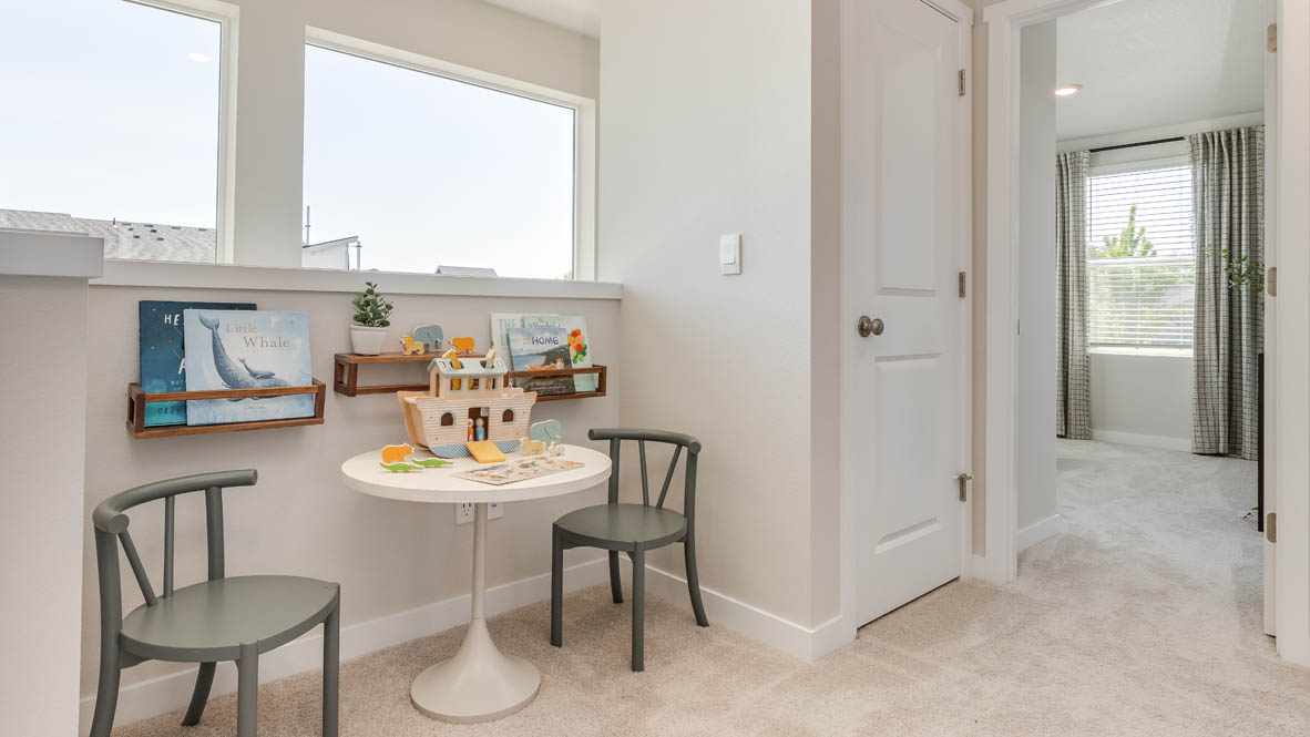 Gordon Creek Pointe tech niche with small table and two chairs, carpet, and a bedroom in the background