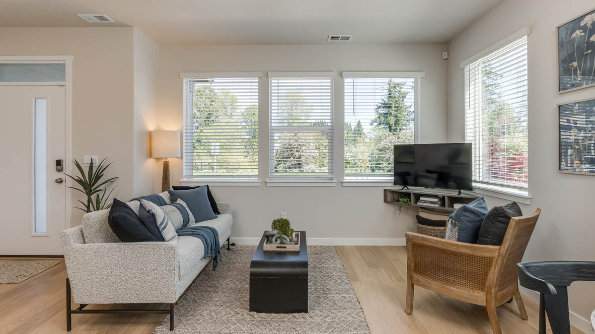 Gordon Creek Pointe Great room with windows, blinds, chair with pillows, tv and entertainment center, picture frames, couch with blanket and pillow, coffee table