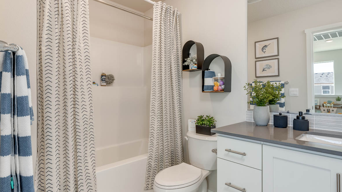 Gordon Creek Pointe bathroom with quartz countertops, shower curtains, toilet, shower tub, cabinets, mirror