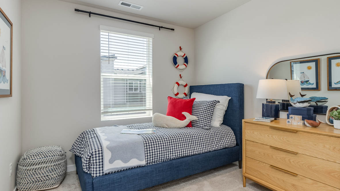 Gordon Creek Pointe bedroom with blue blanket and pillows, plant, windows, and nightstand with lamp