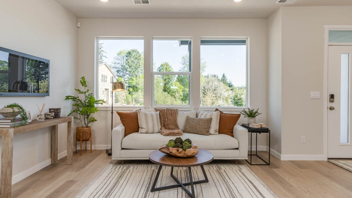 Gordon Creek Pointe Great Room with a coffee table, white couch with pillows, windows, a tv and entertainment center, and a plant